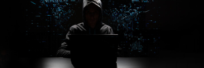 Computer hacker in black mask and hoodie. Obscured dark face. Data thief, internet fraud, cyber...