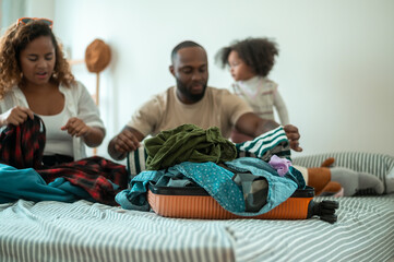 Happy African American Parents with little daughters packing holiday bag of vacation , happy family travel concept