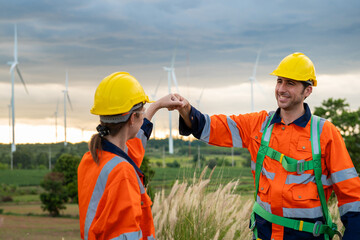  Smart engineers with protective helmet giving fist bump at electrical turbines field