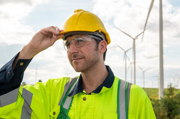 A smart engineer is putting a protective helmet on head at electrical turbines field