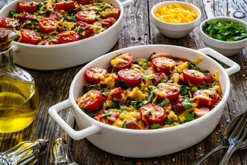 Bread casserole with mozzarella cheese, tomatoes and scrambled eggs on wooden table
