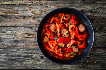 Delicious letcho - vegetables with sausages on wooden table
