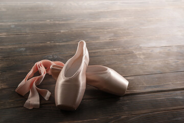 Pointe shoes on a wooden floor, ballet shoes, ballet hall, close-up, copy space, background.

