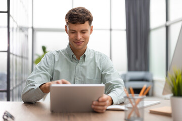 Fototapeta premium Young man using his tablet in the office.