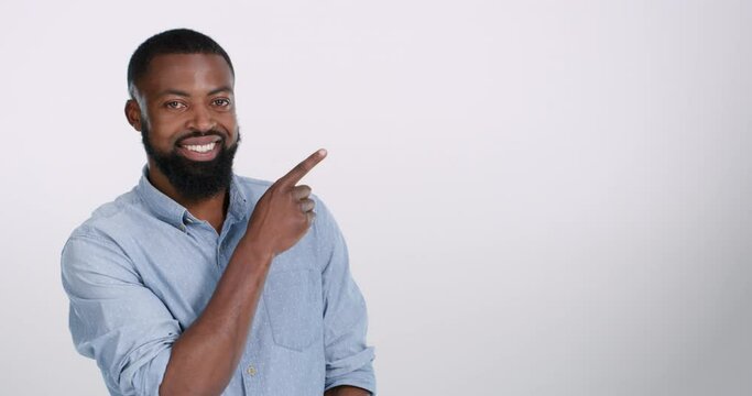 Portrait, pointing and mockup with a black man in studio on a white background for marketing or advertising. Smile, hand gesture or empty branding space with a brand ambassador indoor for advertising