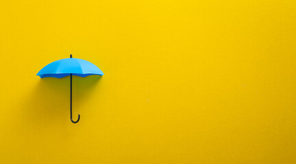 Blue toy umbrella on yellow background.