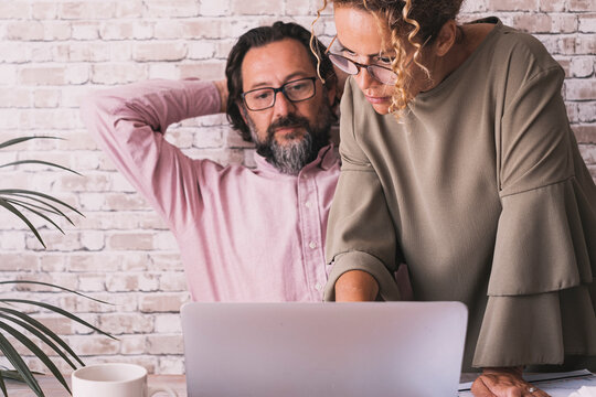 One man having relax stretching shoulder at office while woman colleagues use his computer. Small business team couple concept lifestyle. People using computer for job. Tired worker at the desk
