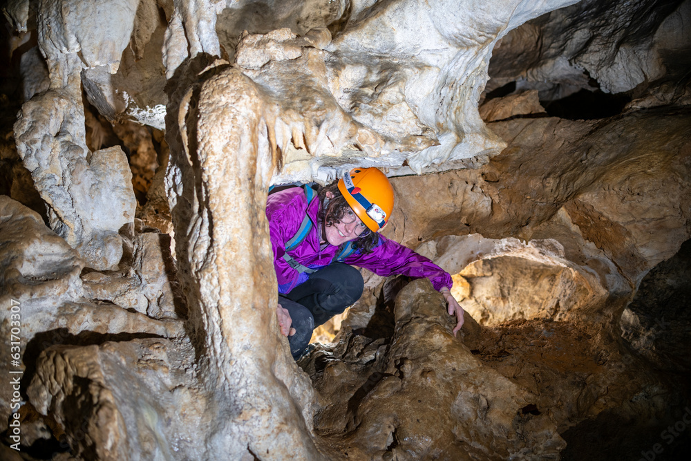 Wall mural Young woman spelunking inside a cave. Feminism concept. Concept of women's sport.