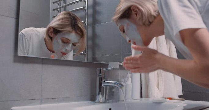 attractive woman washing her face mask from skin, slow motion. Domestic life, wellbeing and selfcare, unaltered. mud mask or homemade multani mitti mask. leisure
