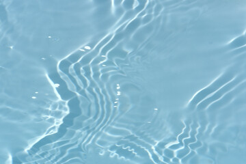 Blue water with ripples on the surface. Defocus blurred transparent blue colored clear calm water surface texture with splashes and bubbles. Water waves with shining pattern texture background.