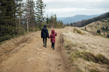 Two children - son and daughter walk around the mountain ridge by the hands