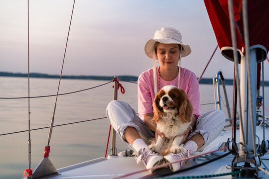 Young woman on a yacht with a dog, Cavalier King Charles Spaniel