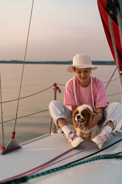 Young woman on a yacht with a dog, Cavalier King Charles Spaniel