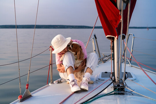 Young woman on a yacht with a dog, Cavalier King Charles Spaniel