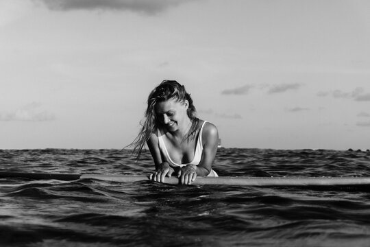 Woman surfer on a surfboard in the ocean waiting for the waves.
