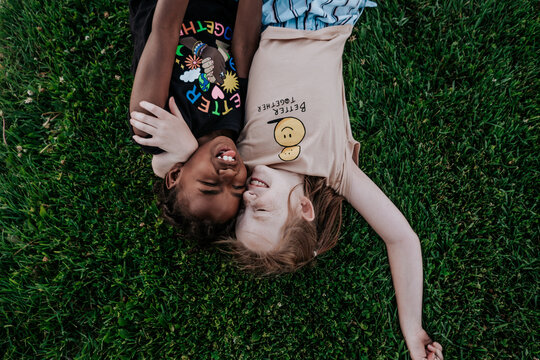 Two girls laying in grass making silly face