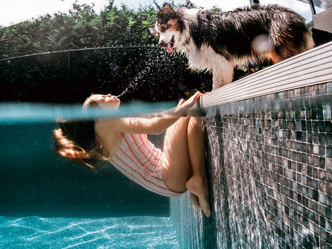 funny image of a girl in the pool splashing water at her dog
