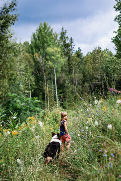 young girl walking with her australian shepperd in a forest