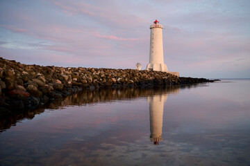 Lighthouse on shore near water in evening