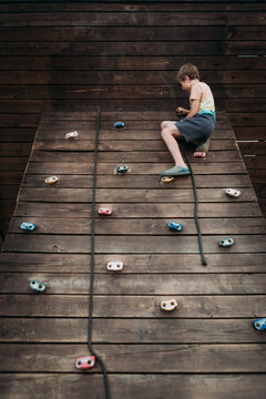 Child climbing rock wall on playground with on summer day