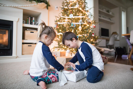 brother and sister work together to unwrap christmas gifts