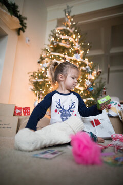 Young girl opens her stocking under the Christmas tree