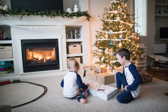 boy and girl opening gifts together under the Christmas tree