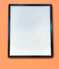 A black poster frame hanging on a peach colored wall