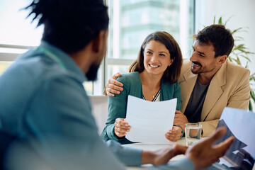 Happy woman and her husband on meeting with insurance agent in office.