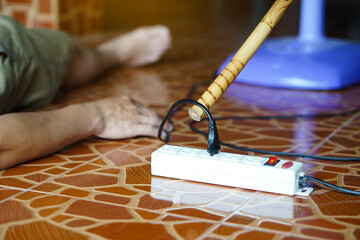 Using stick is moving away the electric plug socket from the unconscious man who lay down on the...
