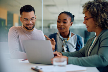 Young multiracial couple and their financial consultant using laptop during meeting in office.