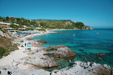 Obraz premium Michelino beach in Calabria, near Tropea, with its crystal clear Caribbean sea. Swimmers relax by sunbathing and taking refreshing baths