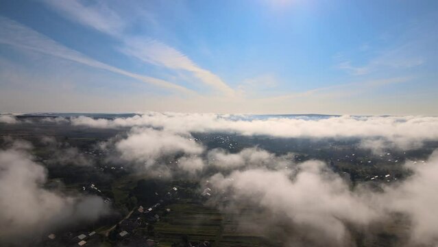 Aerial view from high altitude of landscape covered with puffy morning fog. Cold humid air condensing in rain clouds