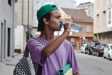 teenage student with bottle of water in the street