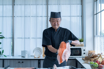 The big salmon is in the hands of the chef cook. Chef cutting fish and making sashimi.