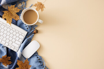 Cozy autumn desk setup idea. Top view arrangement of keyboard, coffee mug, comfortable plaid, computer mouse, yellow leaves on pastel beige background with empty space for promo or text