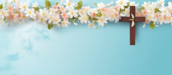 Wooden Cross adorned with Spring flowers on a blue background. Copy space available. Religious background representing Church holidays in Christianity such as Easter, Palm Sunday, Christening, and