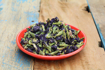 Dried blue butterfly pea flowers in a plate on wooden background 
