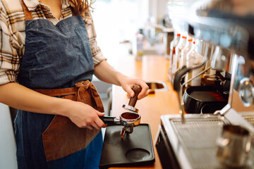 Portrait of a young barista woman making fresh coffee. Takeaway food. Professional coffee making. Small business concept.