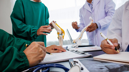 Multiracial medical team having a meeting with doctors in white lab coats and surgical scrubs seated at a table discussing a patients records