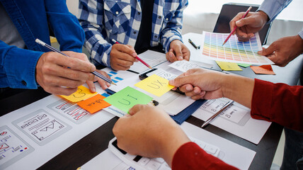 Close-up ux developers and ui designers use augmented reality to brainstorm on mobile app interface wireframe designs on modern office desks. Creative digital development office