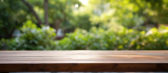 Naklejka premium An empty wooden table is placed outdoors in a garden, with a blurred background. The table is clean and offers ample space for text, making it suitable for marketing and promotional purposes. It