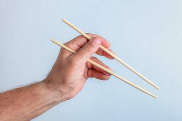 chinese chopsticks in a man's hand on a white background