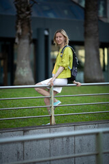 A woman in a white skirt sits on the railing near the crosswalk.