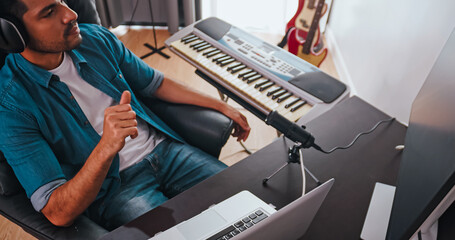 Asian musician is creating new music in his home studio. A composer is using modern equipment to help create a melody.