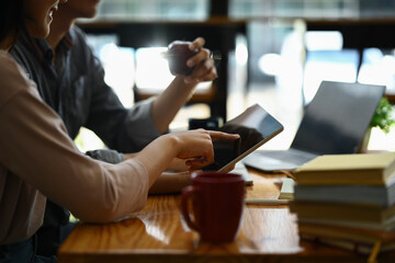 Cropped shot of university students using digital tablet, discussing research, learning tasks together.