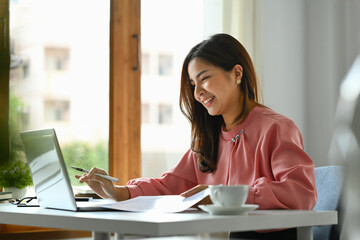 Charming asian woman working on online marketing, using laptop computer at workplace.