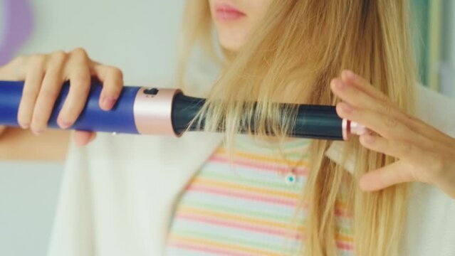 Young caucasian woman making hairstyle using hair dryer at home. 