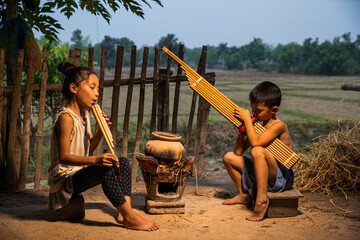 Rural children playing with blowing music and laughter. People Thailand. Boys and girls playing folk music with local instruments.