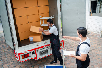 Unloading boxes and furniture from a pickup truck to a new house with service cargo two men movers...